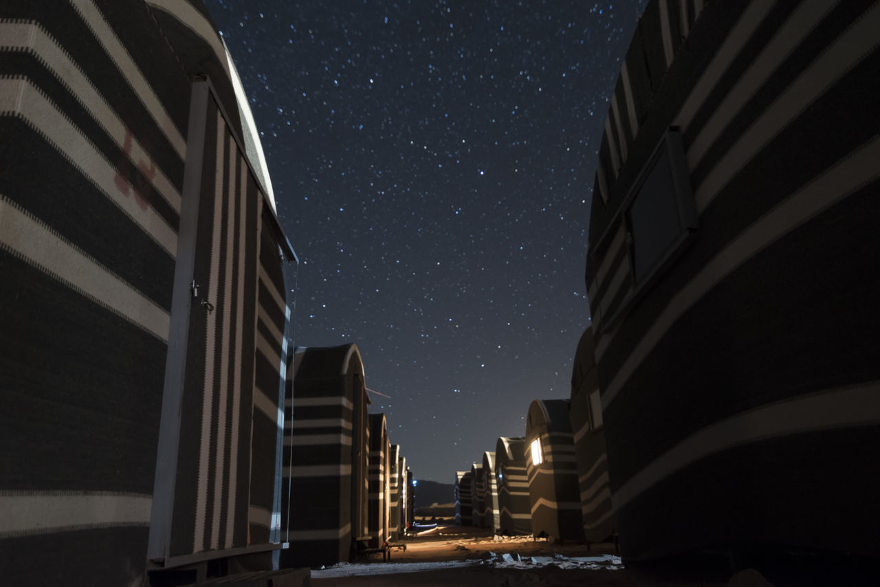 LOW ANGLE VIEW OF ILLUMINATED BUILDINGS AGAINST SKY AT DUSK