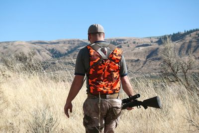 Rear view of man standing on landscape against clear sky