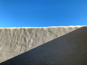 Low angle view of wall against clear blue sky