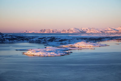 Aerial view of sea against snow covered mountains during winter