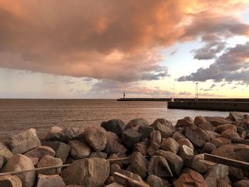 Rocks by sea against sky during sunset