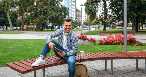 Portrait of young man sitting on bench in park