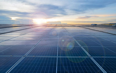 Sunset rays over a photovoltaic power plant, solar panels on a roof , green clean energy concept.