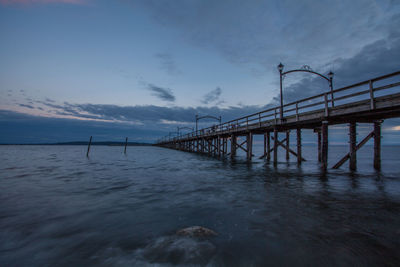 Pier on sea against cloudy sky
