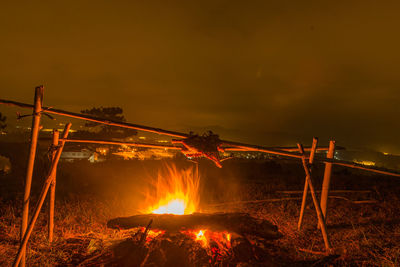 Bonfire on field against orange sky