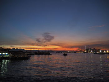 Boats moored at harbor during sunset