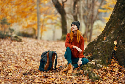 Young woman sitting on autumn leaves