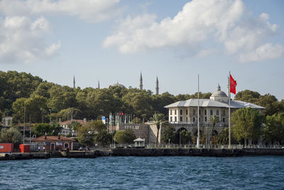 View of buildings at waterfront against cloudy sky