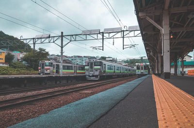 Train at railroad station in city against sky