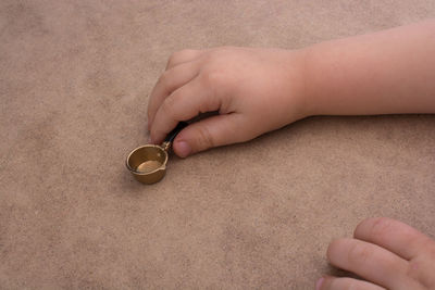 Cropped hand of girl holding toy utensil on floor