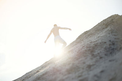 Low angle view of person on rock against sky