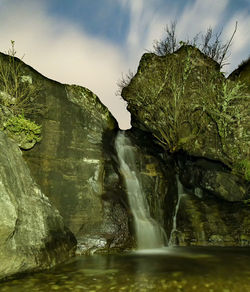 Scenic view of waterfall against sky