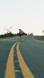 Full length of woman standing on road against sky