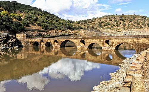 Arch bridge over river against sky