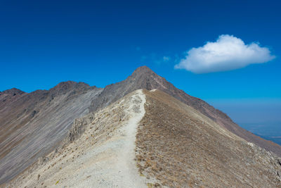 Scenic view of mountain against blue sky