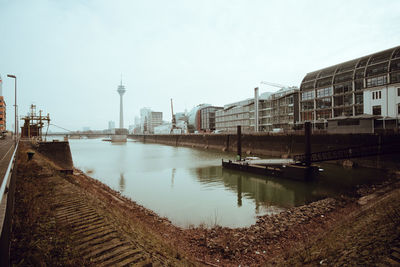 Bridge over canal by buildings in city against clear sky