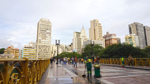 People on modern buildings in city against sky