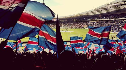 Group of people flags in row against sky