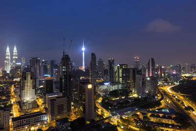 Illuminated menara kuala lumpur tower against sky in city at night