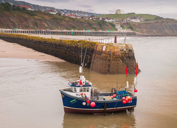 Boats moored on sea against mountains