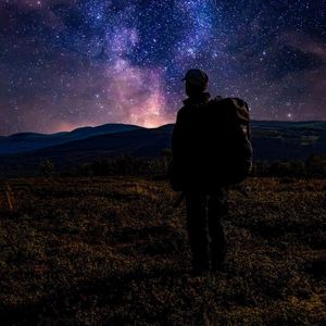 Man standing on mountain against star field