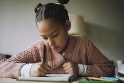 Girl with pigtails coloring on book at home