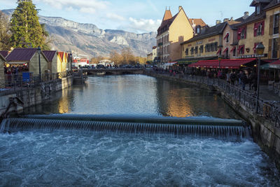 River by buildings in city against sky