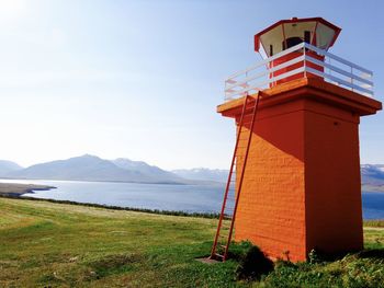 Lighthouse by sea against clear sky