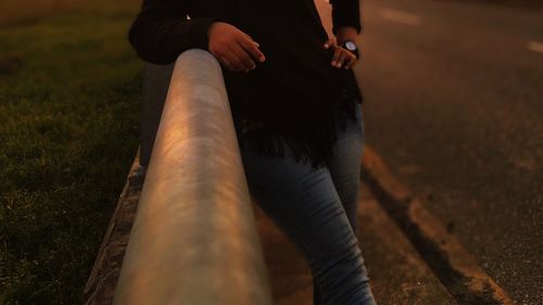 Midsection of woman leaning on railing at night