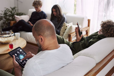 Family relaxing in living room and using phones and tablet