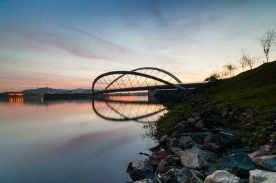 Bridge reflecting on river during sunset