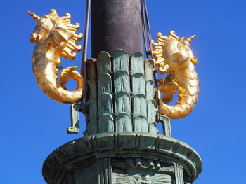 Low angle view of sculpture against clear blue sky