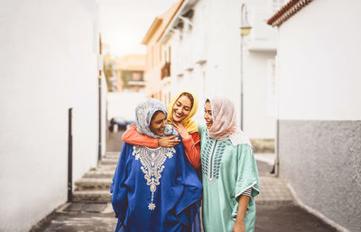 Smiling young woman with friends wearing traditional clothing at alley in city