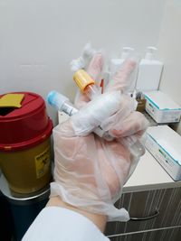 Cropped hand of scientist holding test tubes while gesturing peace sign in laboratory