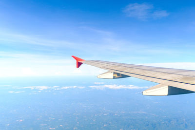 Close-up of airplane wing against cloudy sky