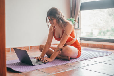 Side view of young woman using laptop at home