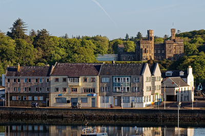 Buildings by river against sky