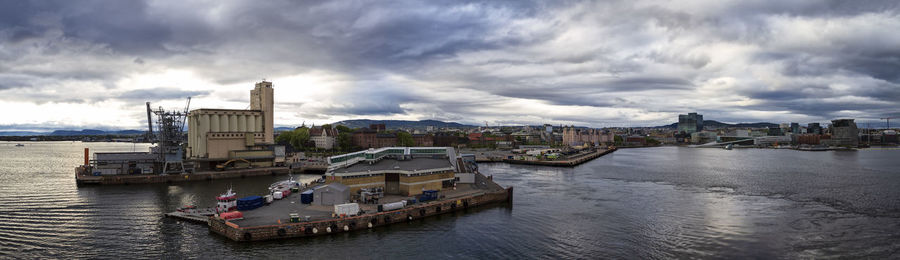 Boats in river by buildings in city against sky