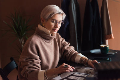 Fashion woman in brown oversize sweater working in modern work place or office with laptop