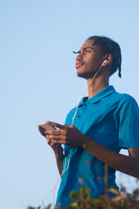 Side view of man using mobile phone against clear sky