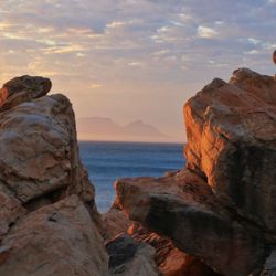 Rock formation on beach against sky during sunset