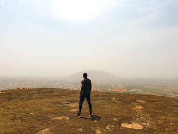 Rear view of man standing on mountain against sky