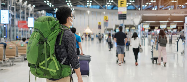 Rear view of man wearing mask standing at airport