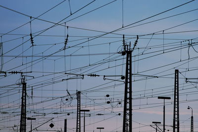 Low angle view of electricity pylons against sky