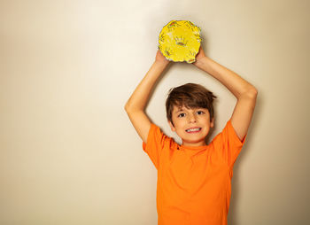 Portrait of boy holding heart shape against wall