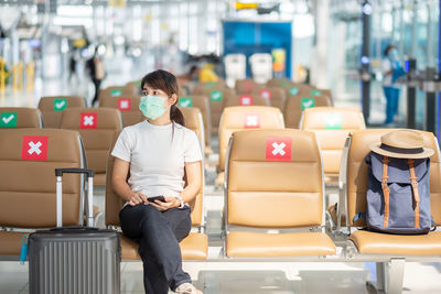 Full length of woman sitting on seat in airport