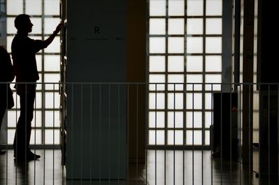 Silhouette man standing by bookshelf in library