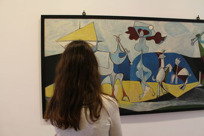 Rear view of woman standing against yellow wall