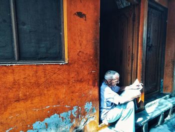 Man sitting on window of building