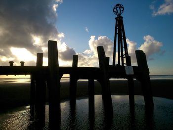 Silhouette pier on beach against sky during sunset